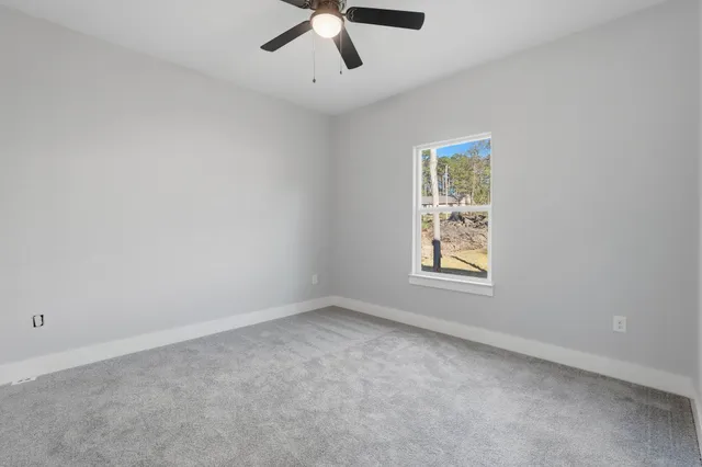 an empty room with a window and a ceiling fan