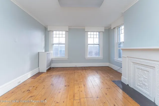 a view of empty room with window and wooden floor