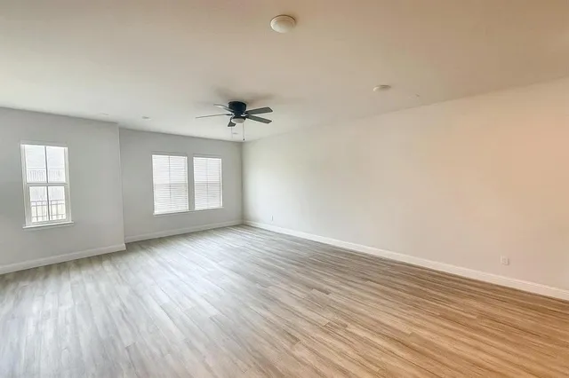 an empty room with wooden floor and windows