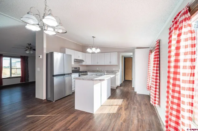 a kitchen with stainless steel appliances granite countertop a refrigerator a sink dishwasher a stove with white cabinets and wooden floor