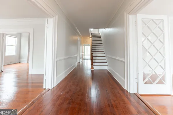 an empty room with wooden floor fireplace and windows