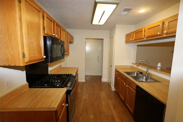a kitchen with stainless steel appliances granite countertop a stove a sink and a microwave