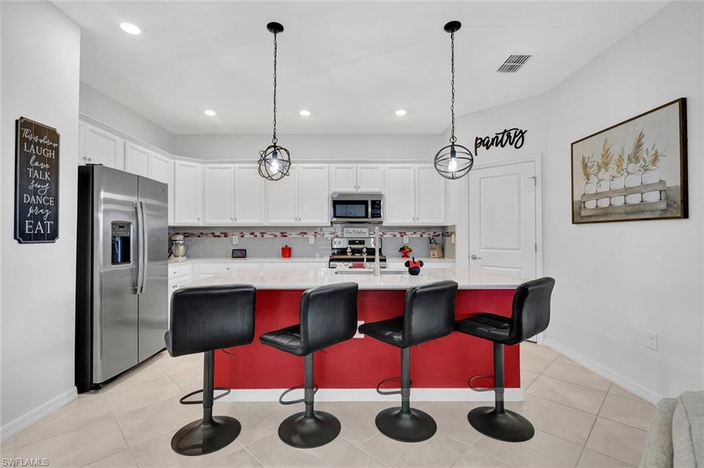 2622 Scarlet Way Naples, FL 34120 - Photo 4 of 24 a kitchen with a sink a refrigerator and chairs