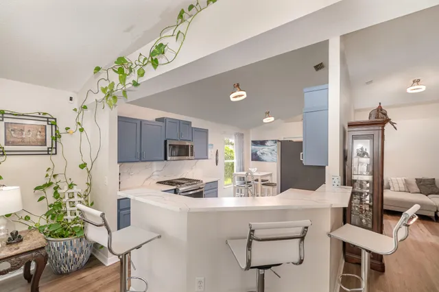 a kitchen with stainless steel appliances kitchen island granite countertop a sink and a refrigerator