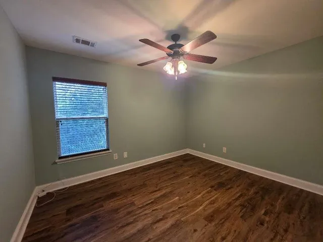 a view of an empty room with window and wooden floor