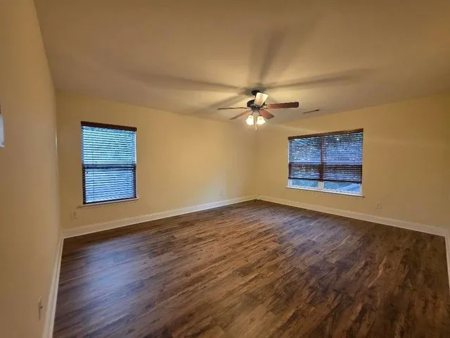 a view of an empty room with a window and wooden floor