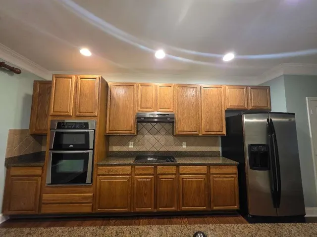 a kitchen with stainless steel appliances granite countertop a refrigerator and a stove