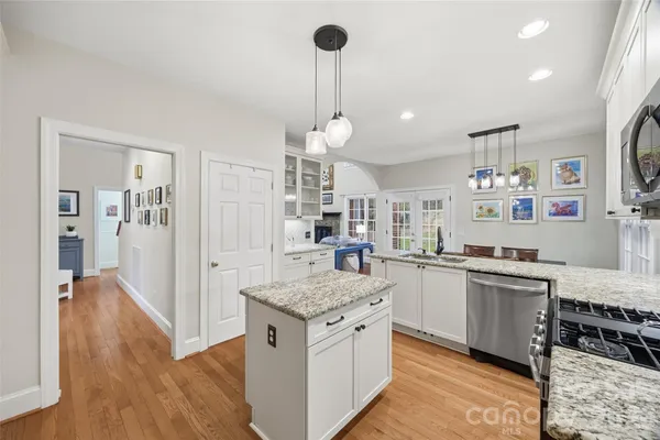 a kitchen with granite countertop kitchen island stainless steel appliances a stove cabinets and wooden floor