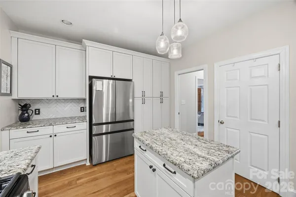 a kitchen with granite countertop stainless steel appliances a stove refrigerator and cabinets