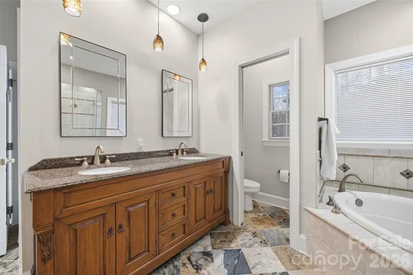 a bathroom with a granite countertop double vanity sink a mirror and a bathtub
