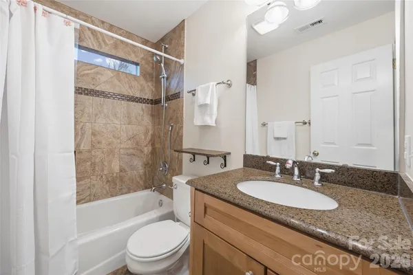 a bathroom with a granite countertop sink toilet and shower