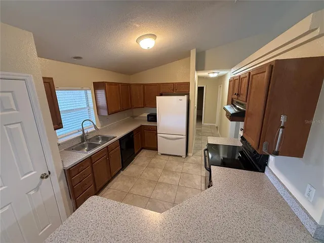 a kitchen with granite countertop a refrigerator and a sink