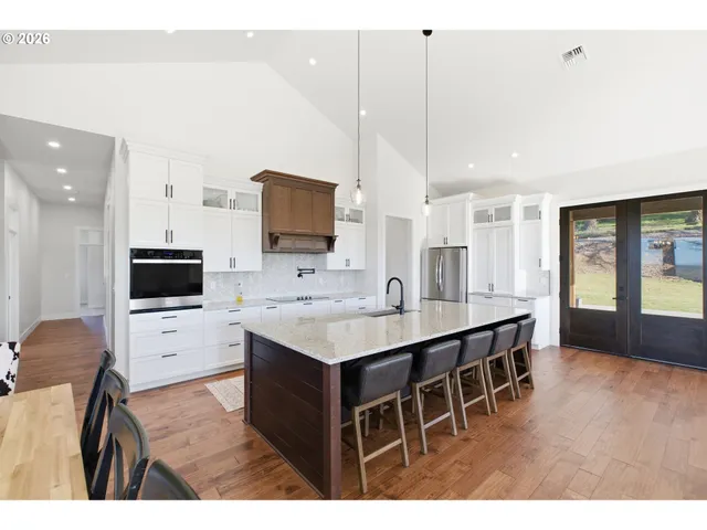 a living room with stainless steel appliances kitchen island a white table chairs and a refrigerator