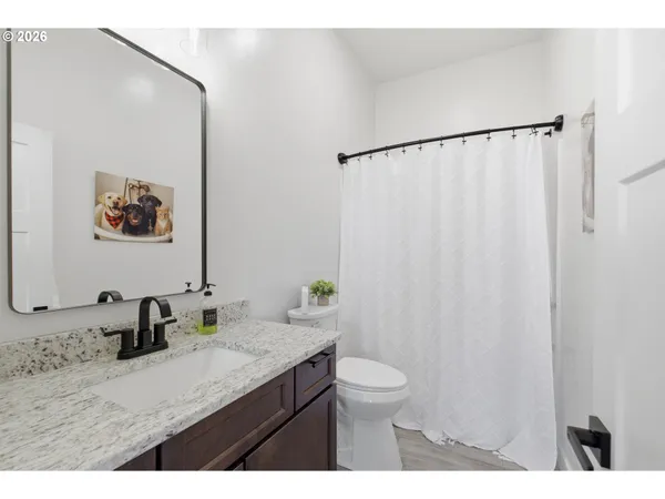 a bathroom with a granite countertop sink a toilet a mirror and shower curtain