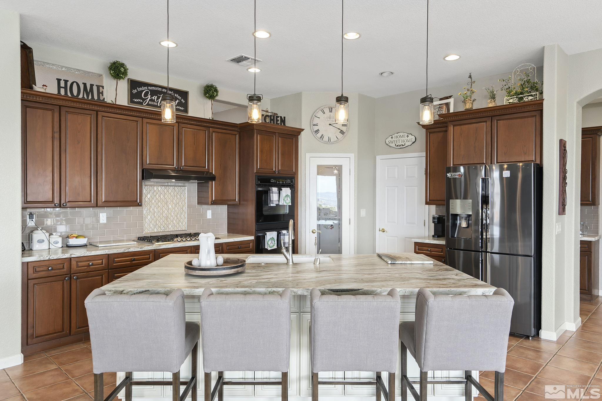 2095 North Tesuque Road Reno, NV 89511 - Photo 15 of 40 a kitchen with stainless steel appliances granite countertop a kitchen island a stove a refrigerator a oven a sink a dining table and chairs