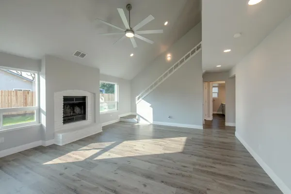 an empty room with wooden floor fireplace and windows