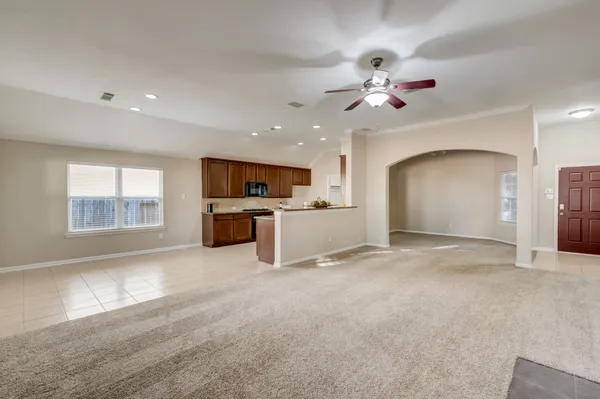 a view of a livingroom with a fireplace a ceiling fan and windows
