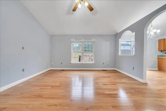 a view of an empty room with wooden floor and window