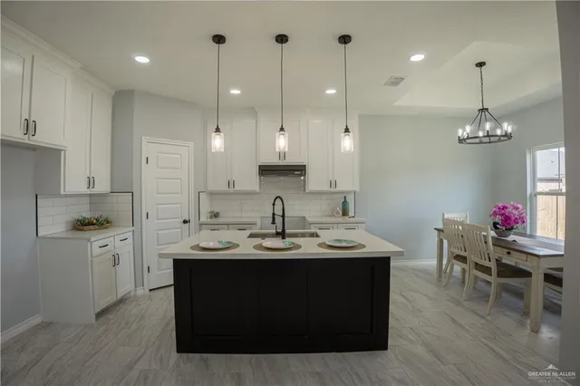 a kitchen with kitchen island stainless steel appliances a dining table chairs sink and stove