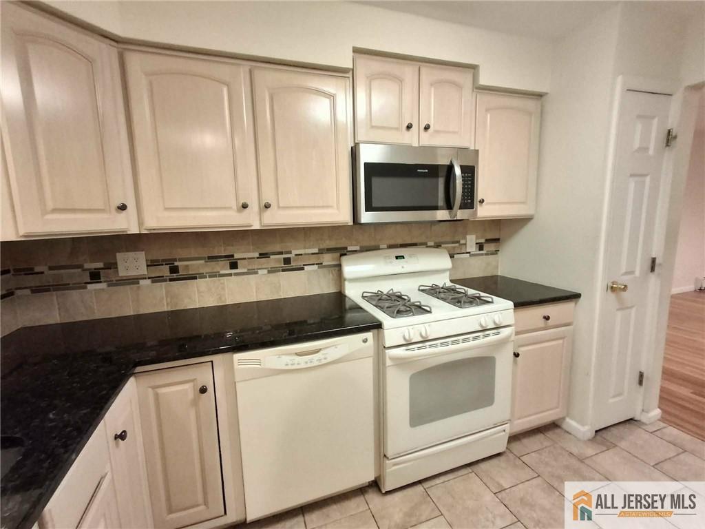 a kitchen with white cabinets and black appliances