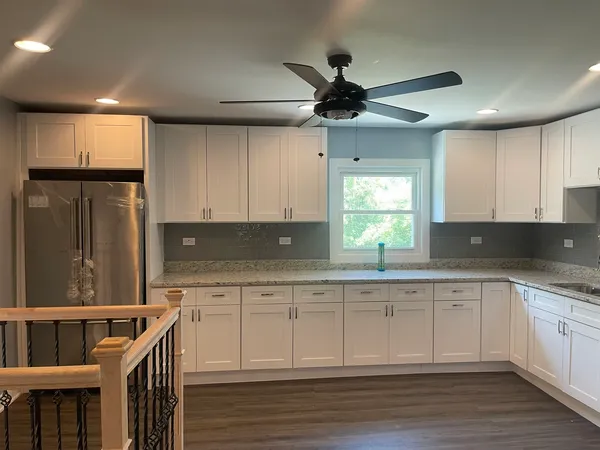 a kitchen with granite countertop a sink cabinets stainless steel appliances and a window