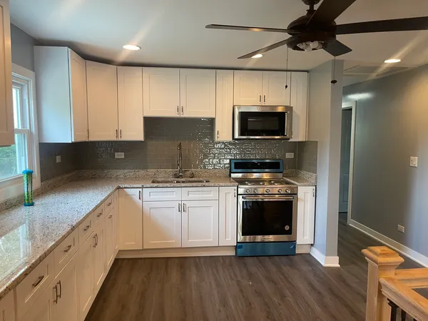 a kitchen with stainless steel appliances granite countertop a stove a sink and a microwave