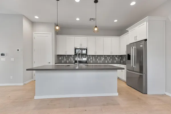 a view of an empty room with kitchen and kitchen view