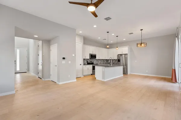 a kitchen with kitchen island granite countertop stainless steel appliances cabinets a sink and a wooden floor