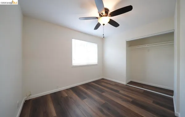 an empty room with a window and a fan
