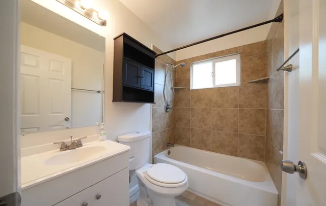 a bathroom with a bathtub shower sink vanity mirror and toilet