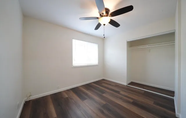an empty room with a window and a fan