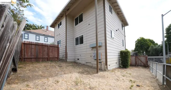 a view of a house with backyard and wooden fence