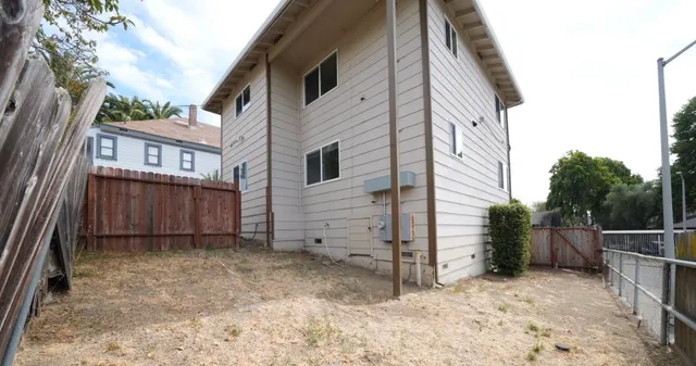 a view of a house with backyard and wooden fence