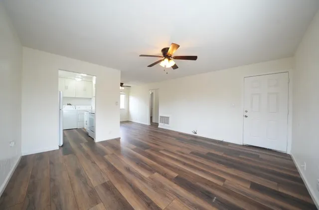 a view of a room with wooden floor and a ceiling fan