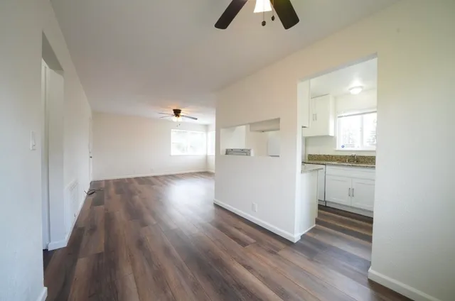 a view of kitchen and empty room with wooden floor