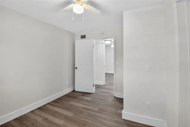 an empty room with wooden floor and ceiling fan