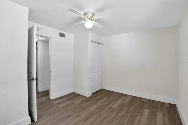 an empty room with wooden floor and ceiling fan
