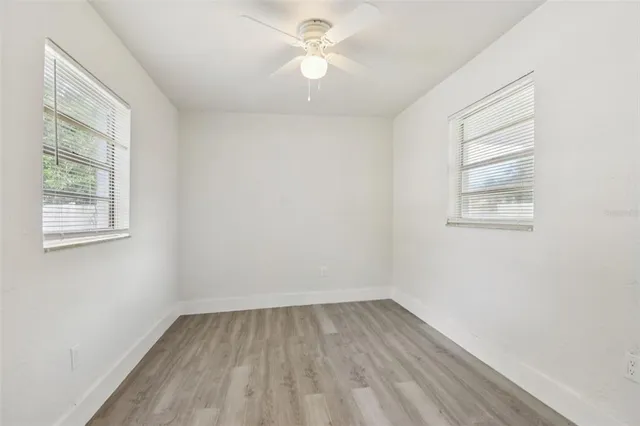 an empty room with a window and a fan