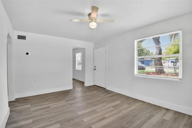 a view of an empty room with wooden floor and a window