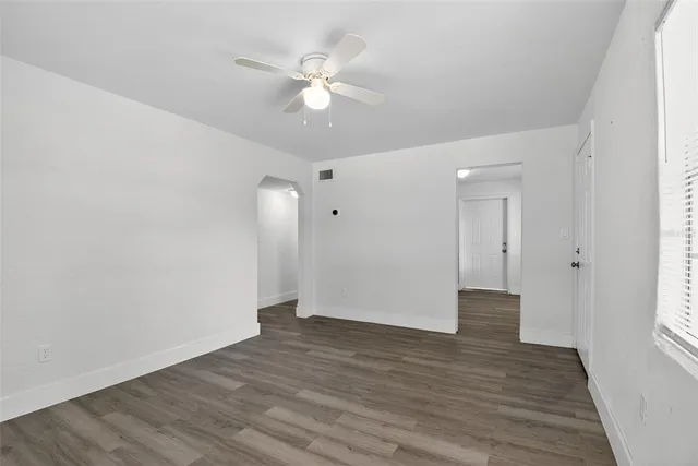a view of an empty room with wooden floor and a window