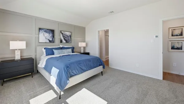 a spacious bedroom with a bed and lamp