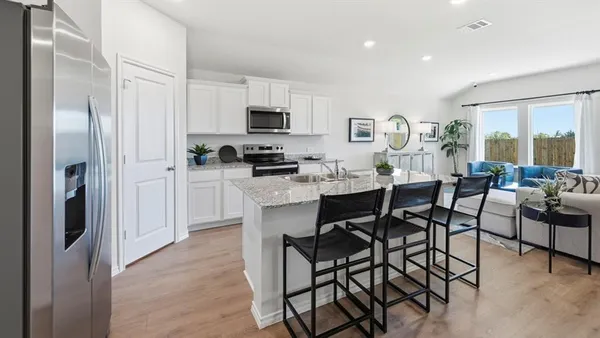 a kitchen with stainless steel appliances a dining table chairs refrigerator and sink