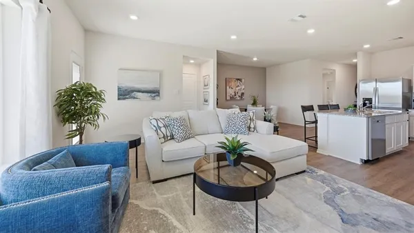 a living room with furniture potted plant and kitchen view