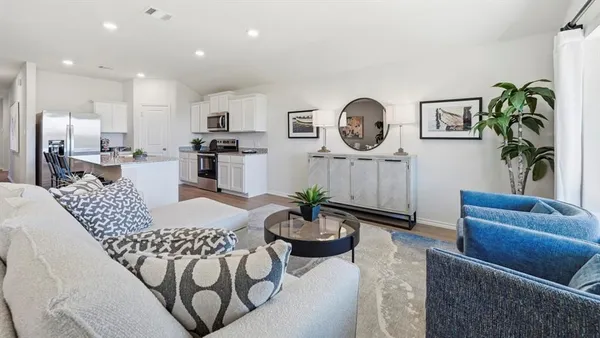 a living room with furniture potted plant and kitchen view