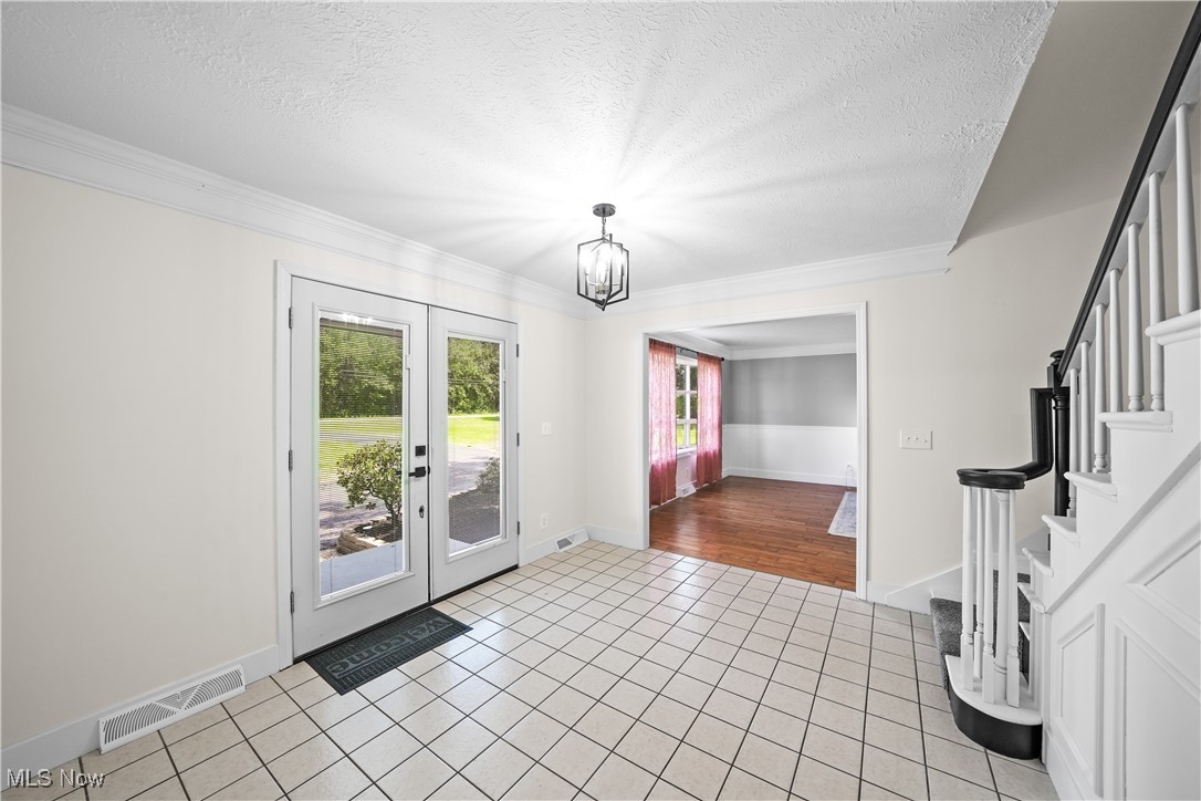 3111 Blake Road Ashtabula, OH 44004 - Photo 23 of 39 Tiled entrance foyer featuring a notable chandelier, french doors, a textured ceiling, and crown molding