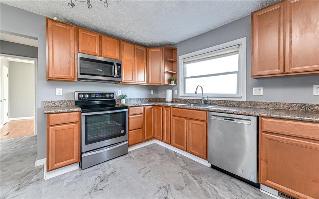 1711 Mercer Street Aliquippa, PA 15001 - Photo 6 of 27 a kitchen with stainless steel appliances granite countertop a stove sink microwave and window