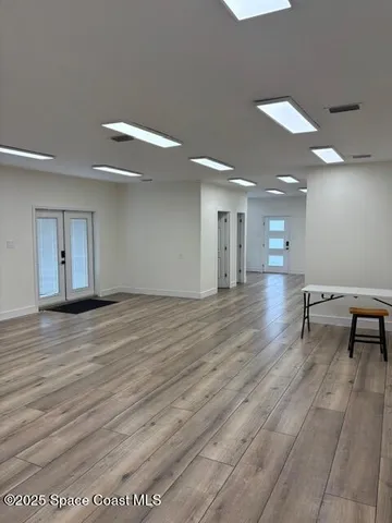 a view of an empty room with wooden floor and window