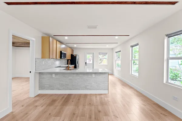 a large kitchen with granite countertop a large window and wooden floor
