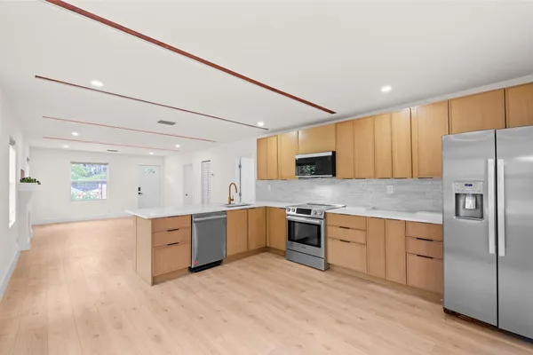a large kitchen with cabinets wooden floor and stainless steel appliances