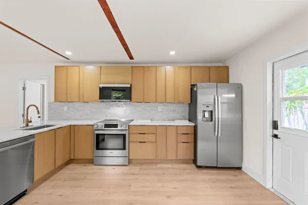 a kitchen with stainless steel appliances granite countertop a refrigerator a sink a stove and cabinets